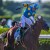 Jockey Victor Espinoza, wearing blue silks with yellow dots and a yellow 'z,' celebrates aboard American Pharoah after winning the Triple Crown at Belmont Park.