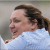 A view from the left side of a smiling Cherie DeVaux, wearing a blue shirt, as she looks to the left.