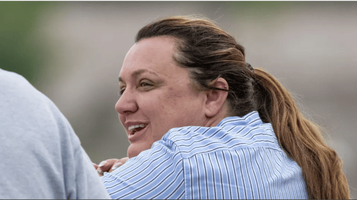 A view from the left side of a smiling Cherie DeVaux, wearing a blue shirt, as she looks to the left.